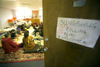 Buddhist monks and volunteers sit side by side, preparing the sungshug, specially prepared pages of scripture that will be placed inside a sacred statue